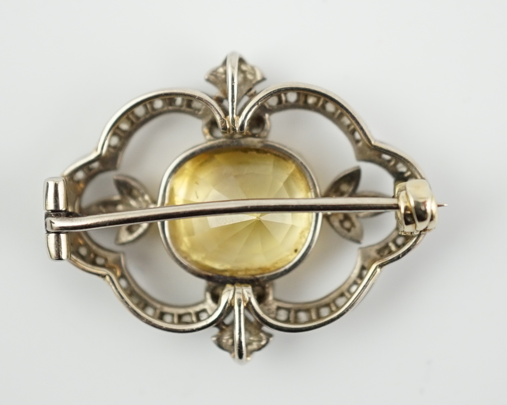 A Belle Epoque white gold, single stone yellow sapphire and diamond chip cluster set open work brooch
